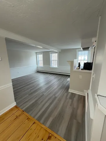 a view of empty room with wooden floor and window