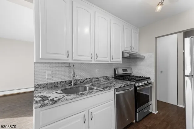 a kitchen with granite countertop white cabinets and stainless steel appliances