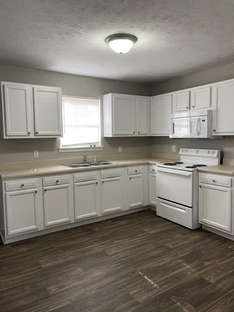 a kitchen with granite countertop white cabinets and white stainless steel appliances