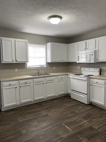 a kitchen with granite countertop white cabinets and white stainless steel appliances