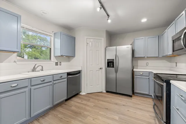 a kitchen with a sink cabinets stainless steel appliances and a window