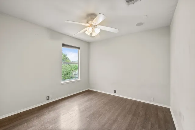 an empty room with a window and a fan