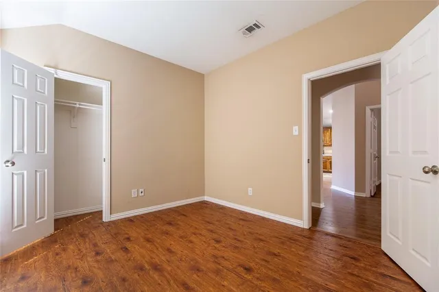 a view of an empty room with wooden floor and closet