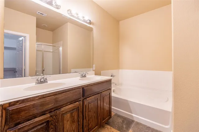 a bathroom with a double vanity sink a mirror and a bathtub