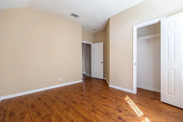 a view of an empty room with wooden floor and closet