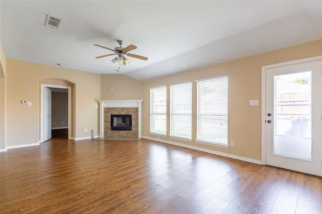 an empty room with wooden floor a ceiling fan and windows