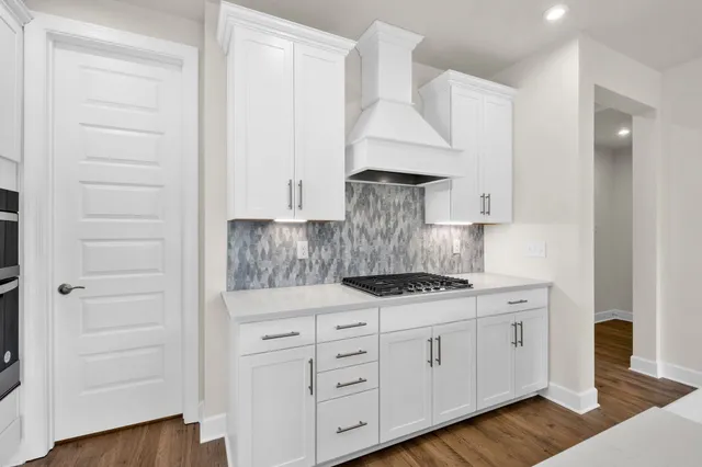 a kitchen with white cabinets and a stove with wooden floor