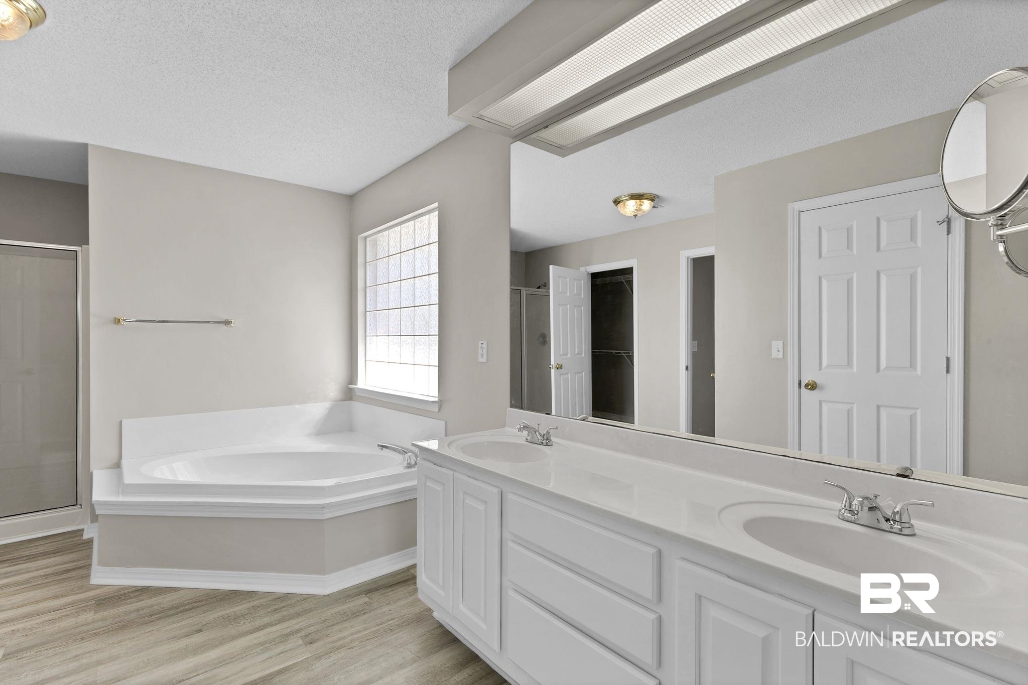 10238 Grove Drive Fairhope, AL 36532 - Photo 15 of 39 Bathroom with 2 walk in closets ( his and hers) , a garden tub, separate shower, private water closet, wood finished floors, and double vanity.
