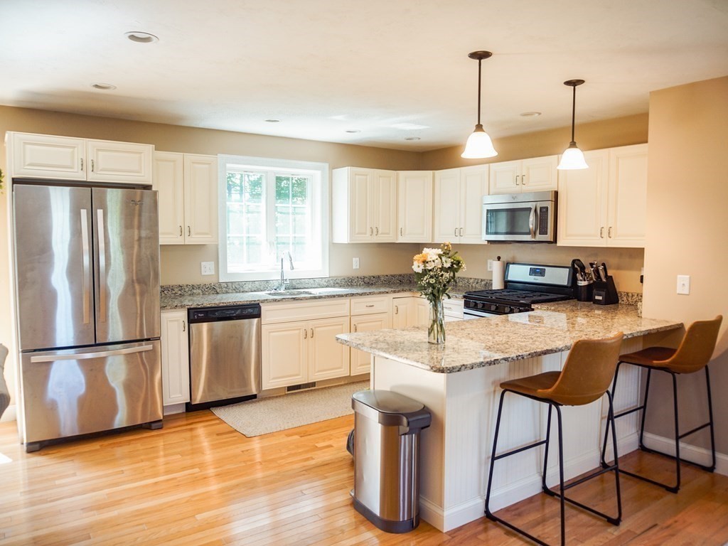 206 Haymeadow Lane Ayer, MA 01432 - Photo 9 of 41 a kitchen with stainless steel appliances granite countertop a refrigerator a stove a sink a dining table and chairs with wooden floor