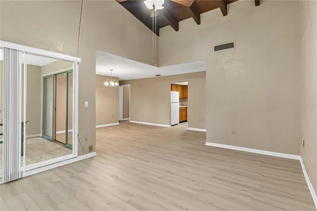 a view of an empty room with wooden floor and a fan