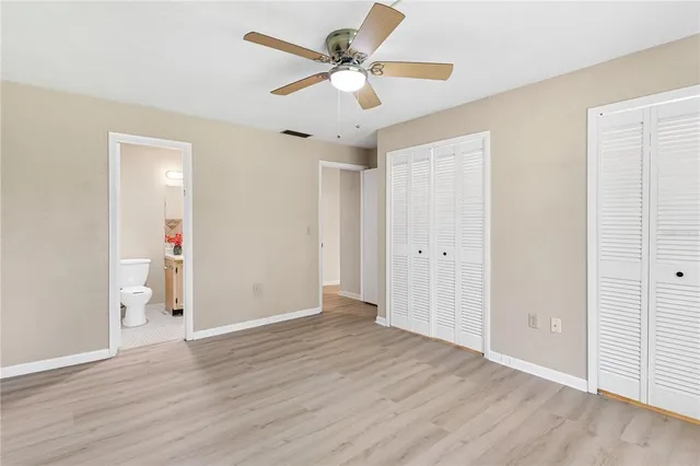 an empty room with wooden floor and ceiling fan