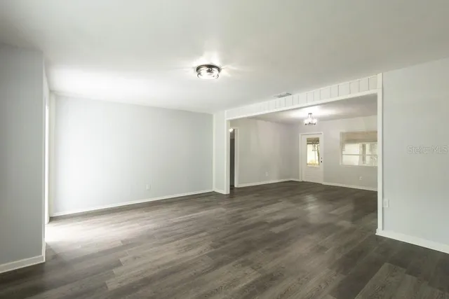 a view of an empty room with wooden floor and closet