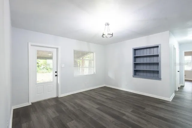 an empty room with wooden floor closet and windows