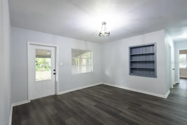 an empty room with wooden floor closet and windows