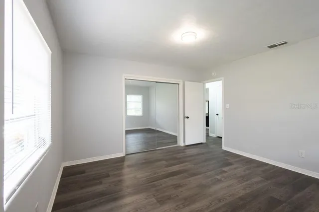 an empty room with wooden floor & windows in it