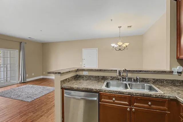 a view of a kitchen with a sink wooden cabinets and a window