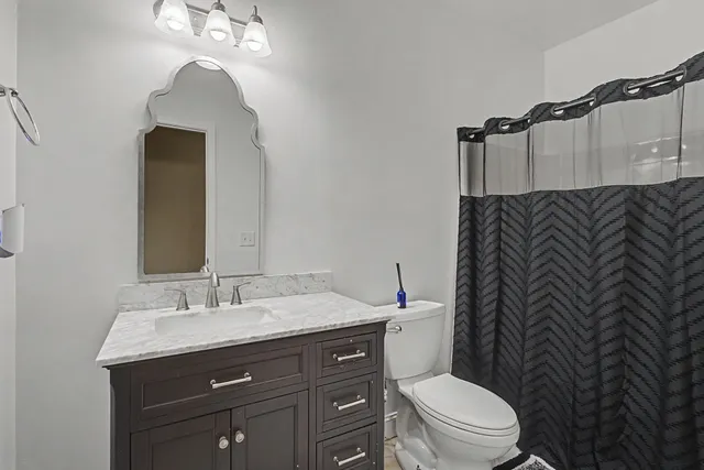 a bathroom with a granite countertop toilet sink and mirror