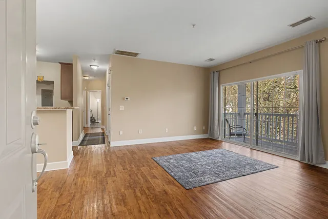 a view of an empty room with wooden floor and a window