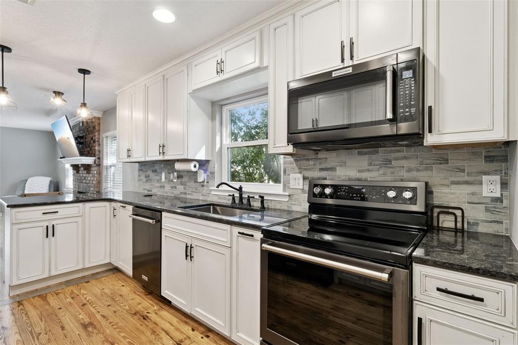 1304 Perkins Road Orlando, FL 32809 - Photo 10 of 22 a kitchen with stainless steel appliances granite countertop a stove microwave and sink