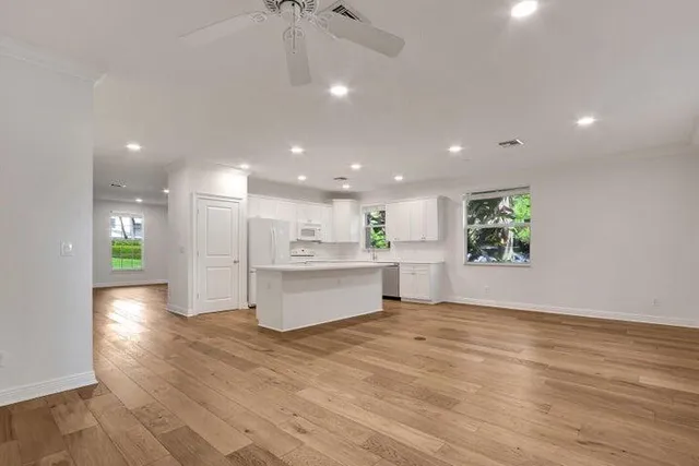 a view of kitchen with kitchen island wooden floor appliances and living room