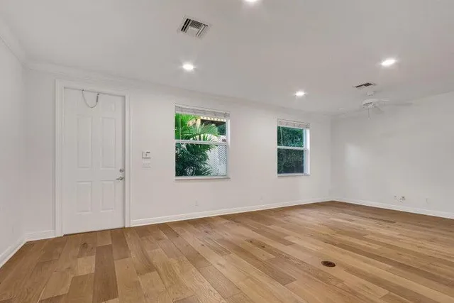 a view of an empty room with wooden floor and a window