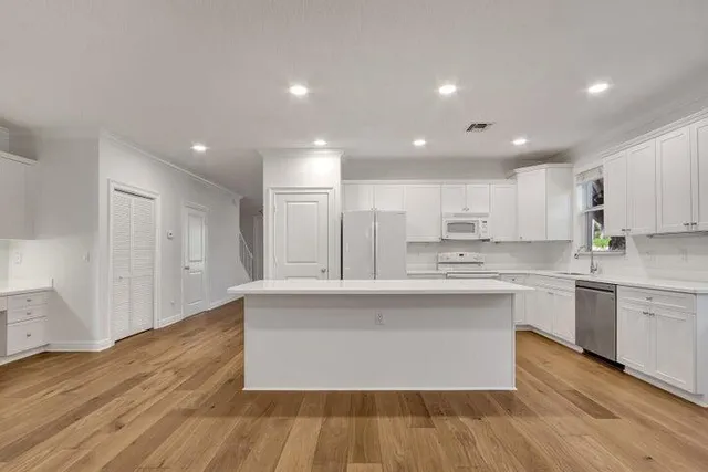 a large kitchen with stainless steel appliances granite countertop a large center island a sink a refrigerator and white cabinets