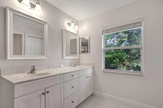 a bathroom with a double vanity sink a mirror and a window
