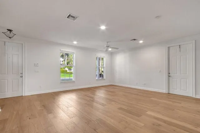 an empty room with wooden floor and windows