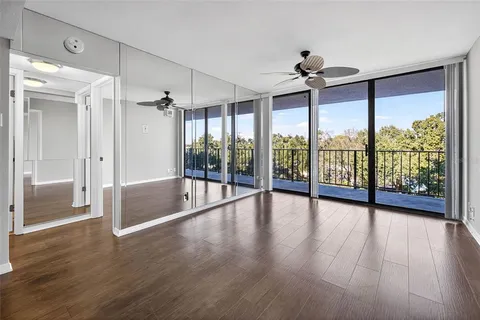 an empty room with wooden floor fan and windows