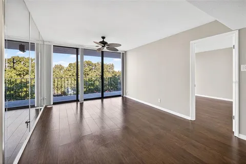 a view of an empty room with a window and wooden floor