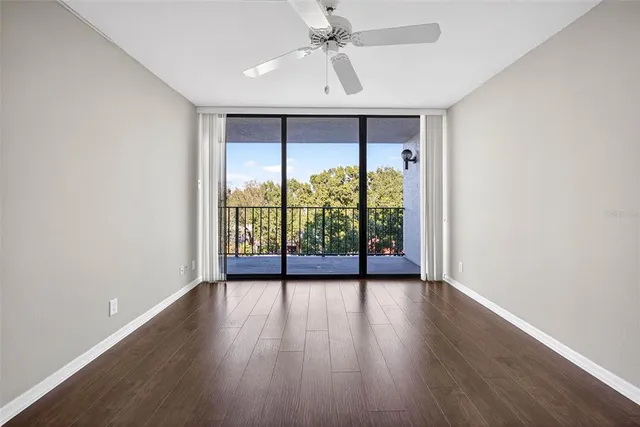 an empty room with wooden floor and ceiling fan