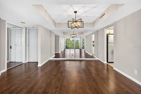 a view of an empty room with wooden floor and fan