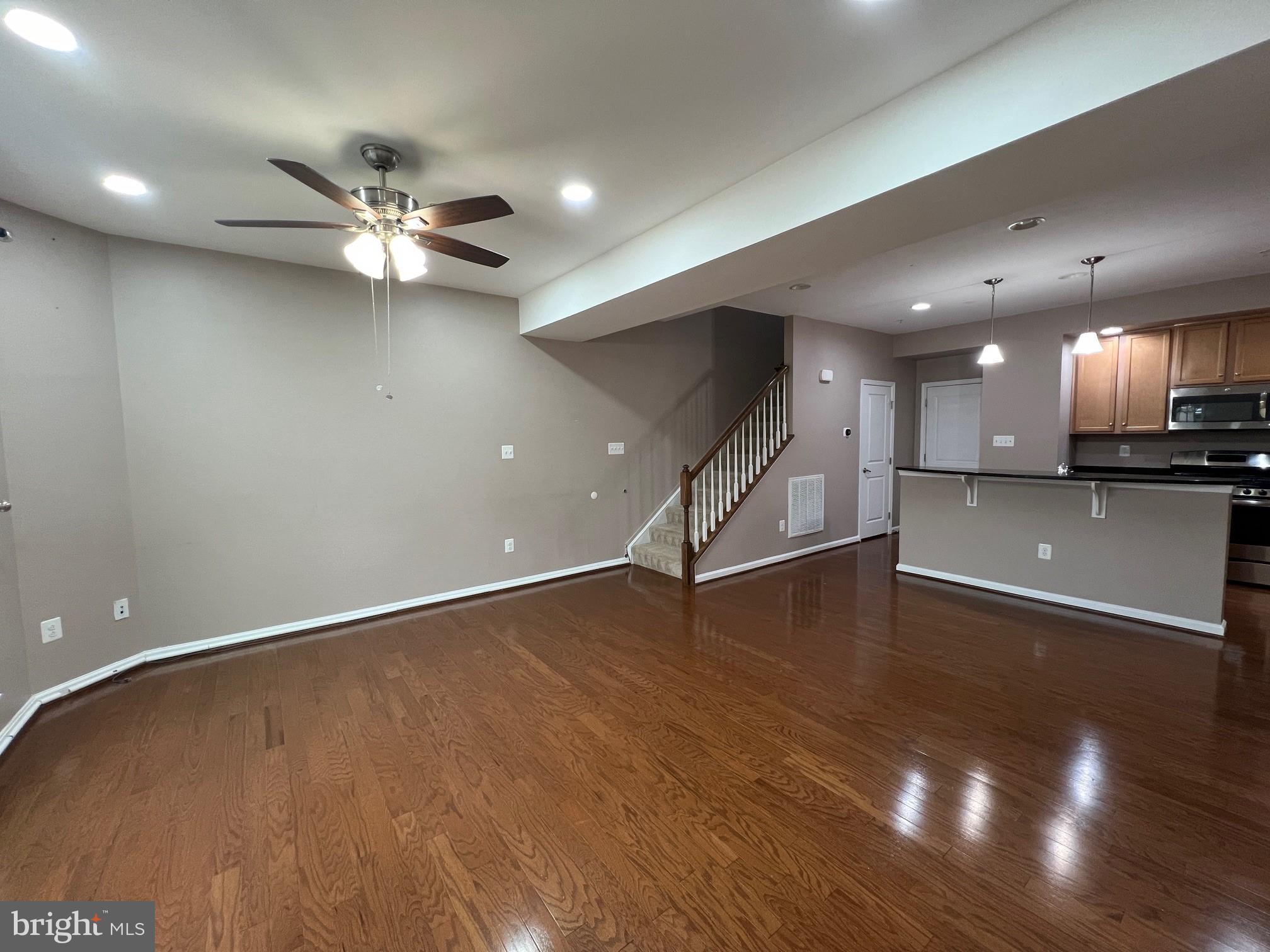5057 Small Gains Way Frederick, MD 21703 - Photo 2 of 22 an empty room with wooden floor a ceiling fan and kitchen view
