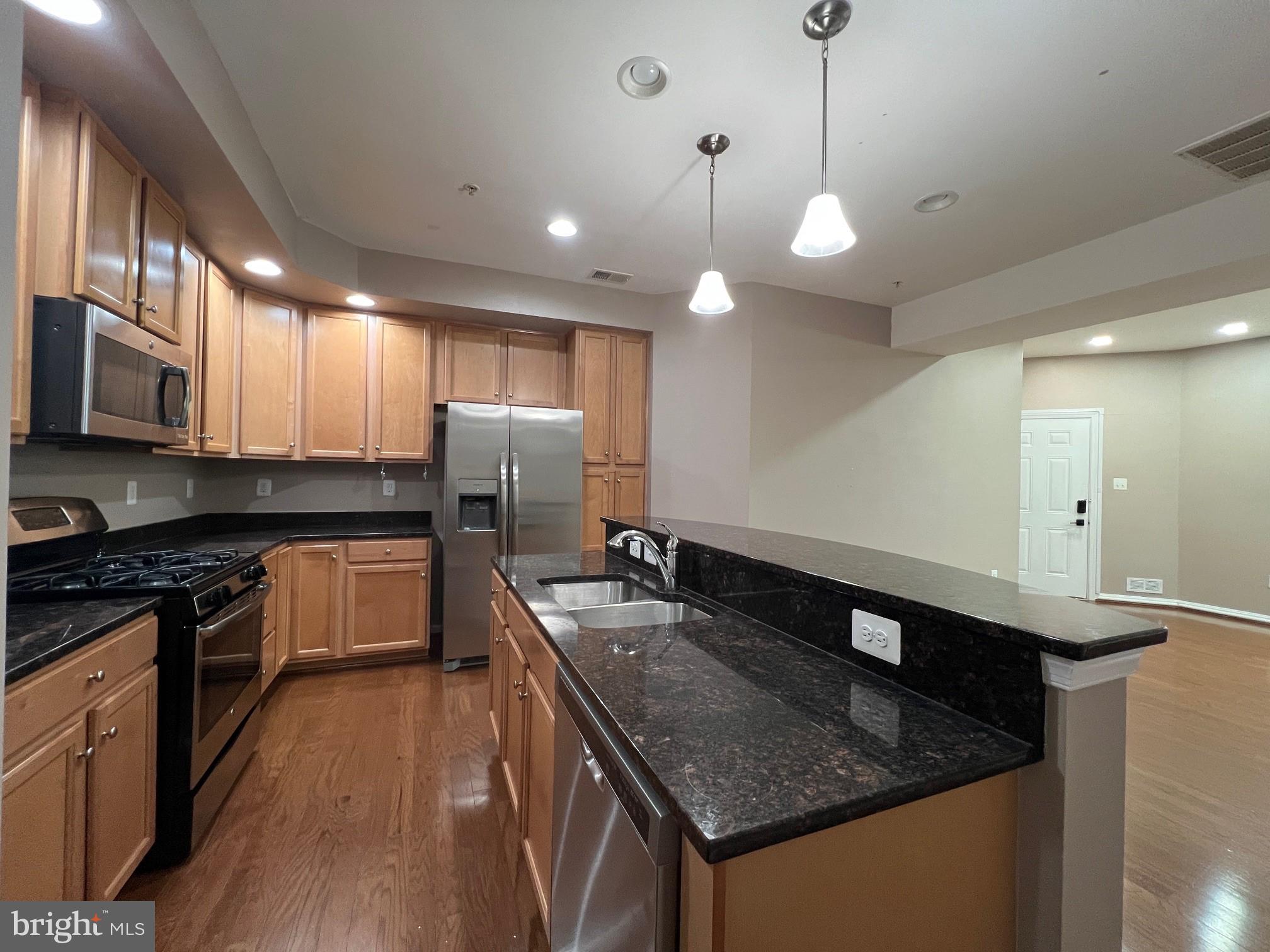 5057 Small Gains Way Frederick, MD 21703 - Photo 5 of 22 a kitchen with stainless steel appliances granite countertop a sink a stove and a wooden floors