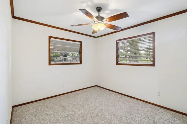 an empty room with a window and a ceiling fan