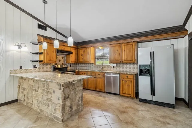 a kitchen with stainless steel appliances granite countertop a refrigerator a sink dishwasher a stove with white cabinets and wooden floor