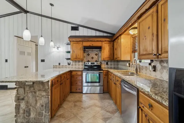 a large kitchen with granite countertop a sink a counter top space appliances and cabinets
