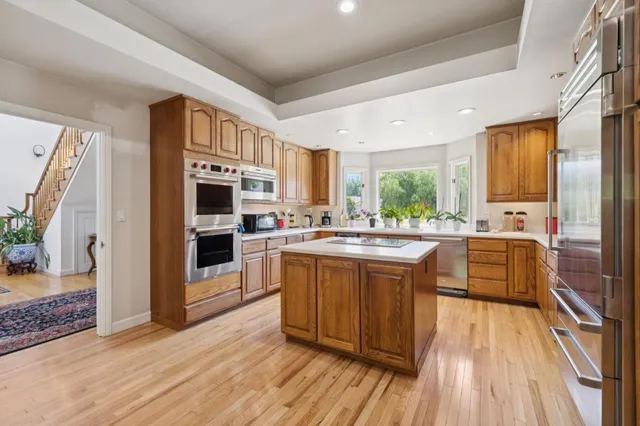 a large kitchen with stainless steel appliances granite countertop a lot of cabinets and wooden floor