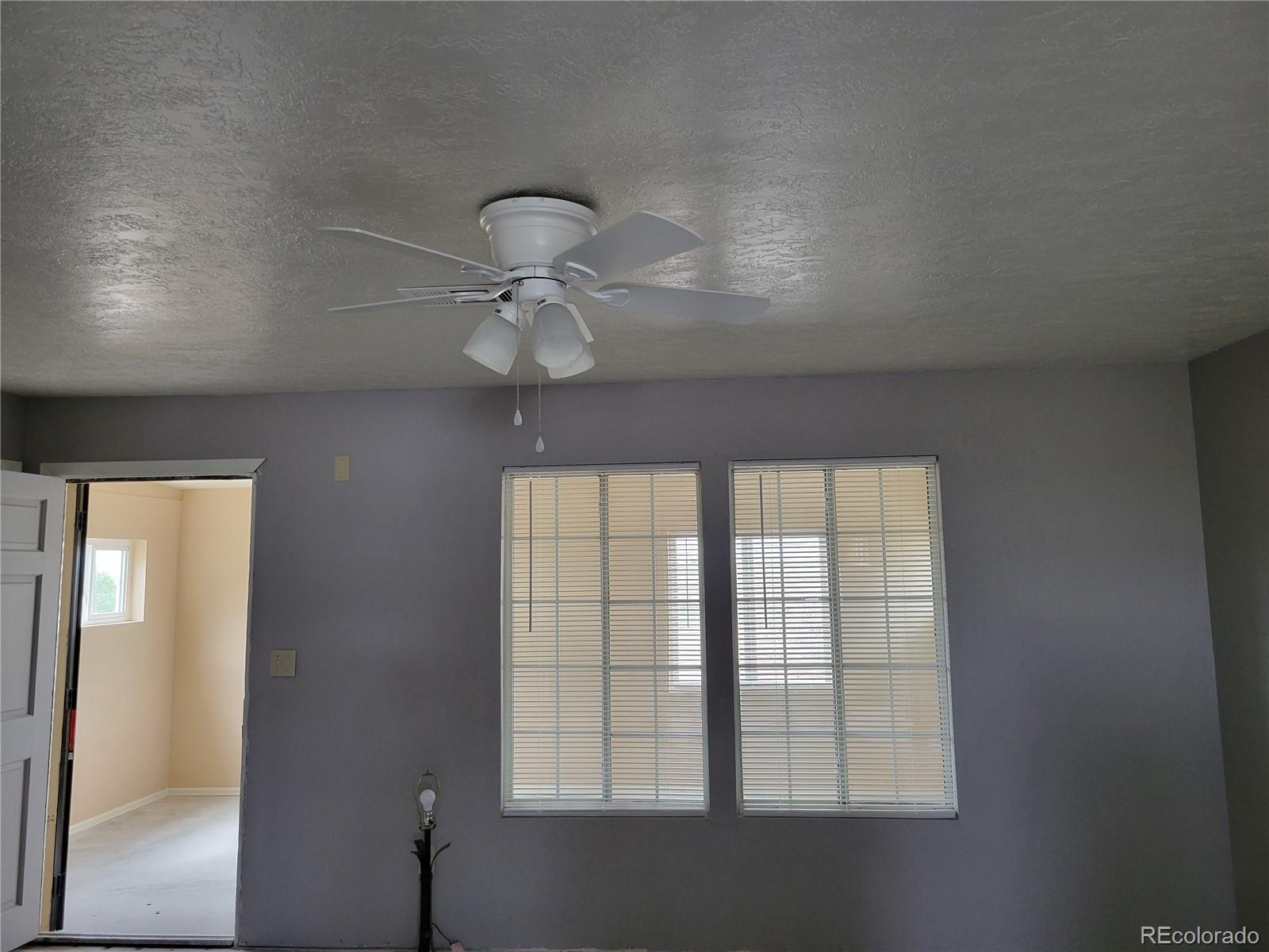 8246 Manitou Springs Road Blanca, CO 81123 - Photo 19 of 24 an empty room with windows and chandelier fan