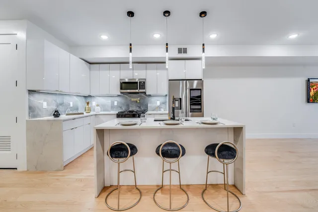 a kitchen with kitchen island granite countertop a sink cabinets and wooden floor