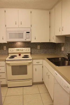 a kitchen with granite countertop white cabinets and stainless steel appliances