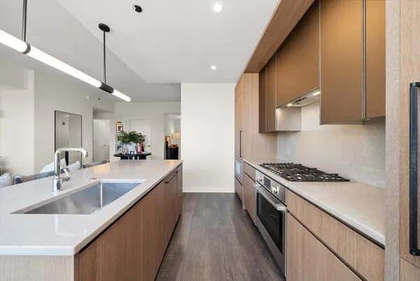 a kitchen with stainless steel appliances granite countertop a sink a stove and a wooden floors