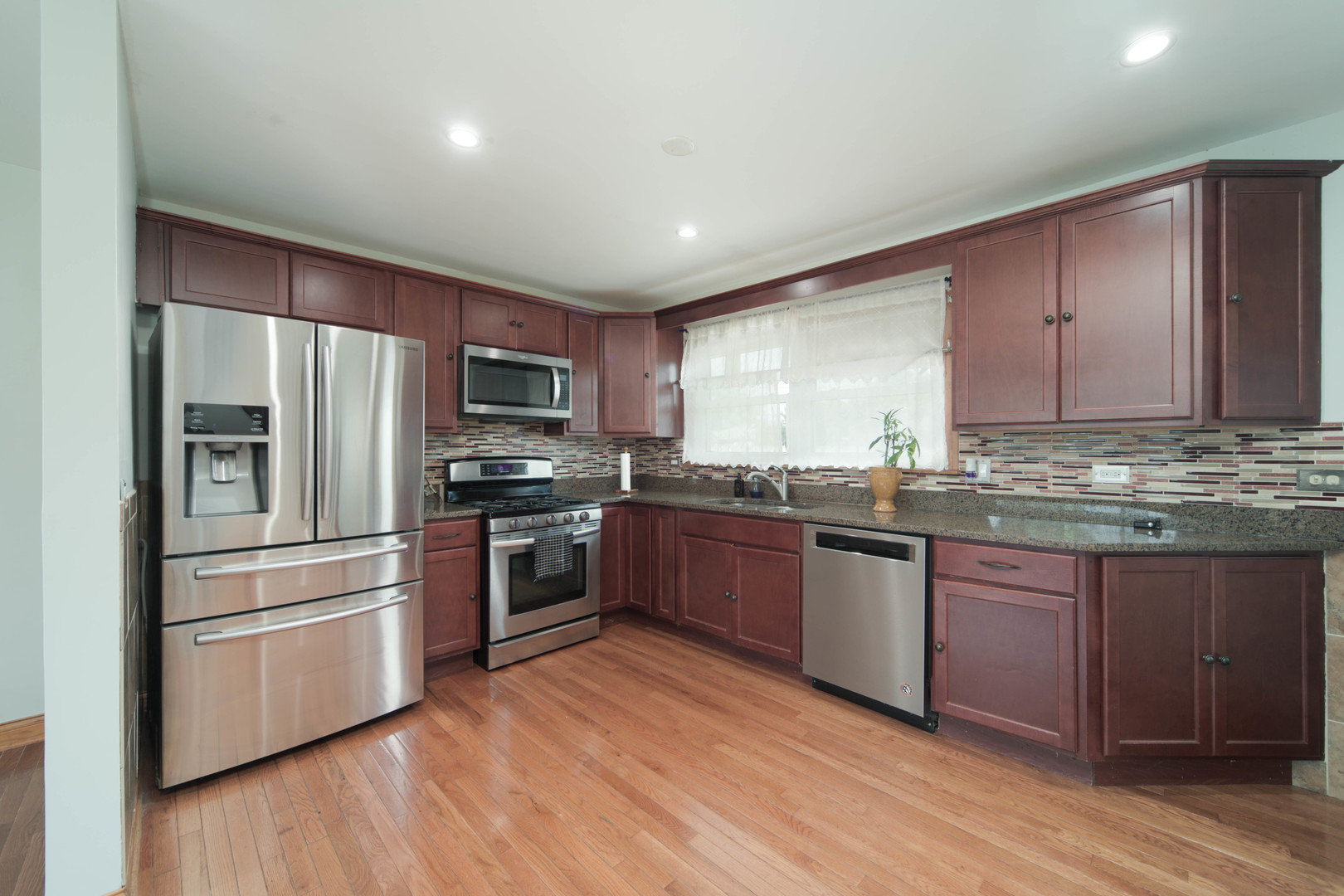 543 Rose Avenue Addison, IL 60101 - Photo 3 of 18 a kitchen with granite countertop stainless steel appliances and wooden cabinets