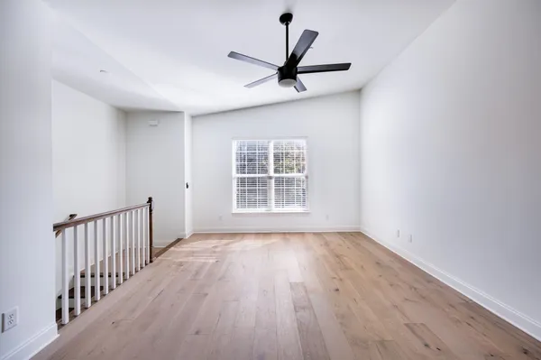 a view of a room with wooden floor a ceiling fan and windows
