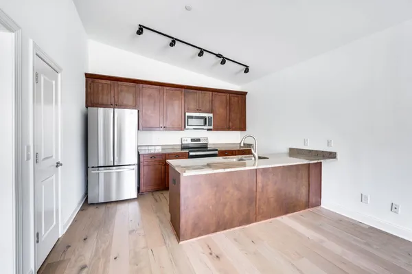 a kitchen with stainless steel appliances a refrigerator stove and wooden floor