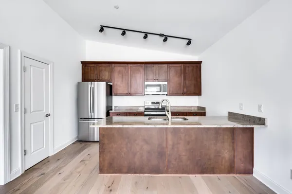 a kitchen with stainless steel appliances granite countertop a refrigerator a stove and a wooden floors