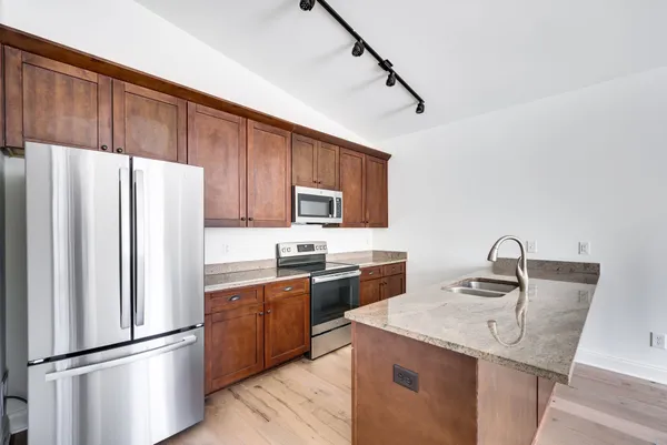 a kitchen with granite countertop a refrigerator stove and sink