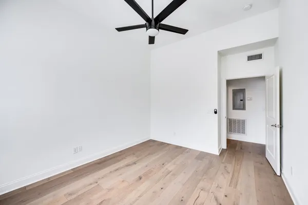 a view of a room with wooden floor and a ceiling fan