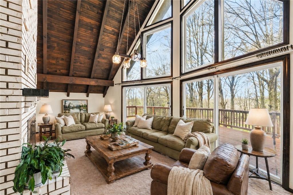255 Claytonia Road Butler, PA 16001 - Photo 11 of 50 VIRTUALLY STAGED - Striking rustic family room with a wood-burning fireplace and soaring vaulted wood ceilings, where a dramatic wall of windows frames tranquil views of the surrounding trees—creating the perfect setting for intimate evenings, relaxed mornings, and cozy nights by the fire.