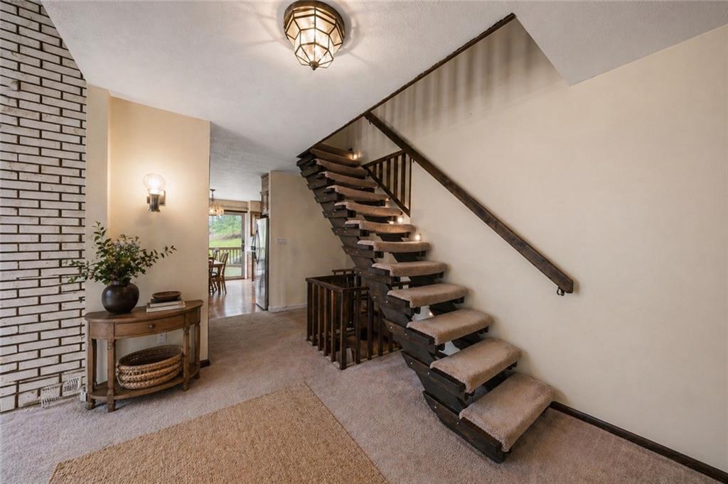 255 Claytonia Road Butler, PA 16001 - Photo 8 of 50 VIRTUALLY STAGED- Step into the main-level foyer, where a striking open-riser staircase with rich wood treads and exposed structure creates an immediate architectural statement.